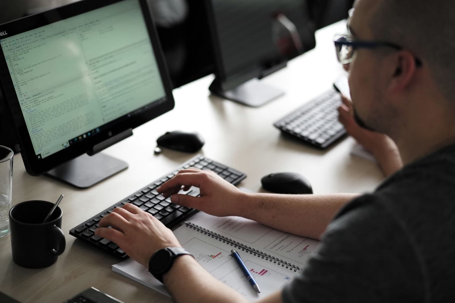 Ruce účastníka na klávesnici, na monitoru rozpracovaný kód